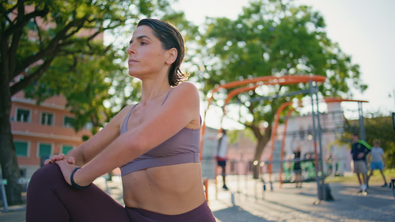 mujer fuerte entrenamiento flexibilidad sol estadio primer plano. mujer estirando las piernas