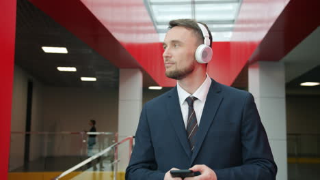 businessman in a modern office building wearing headphones and using a mobile phone