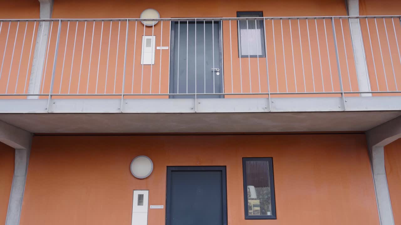Tilt up shot of multistory dormitory building apartment entrances, Denmark