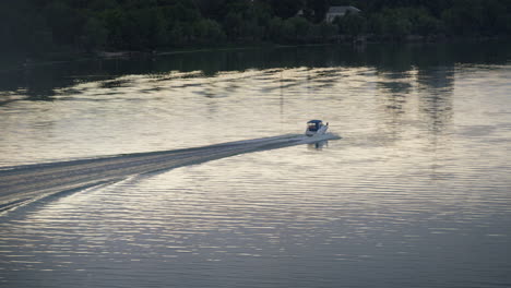 motorboat driving dark river at green tree shore at evening time drone shot.