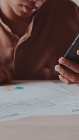 close up of woman hands with mobile phone and business documents lying on table