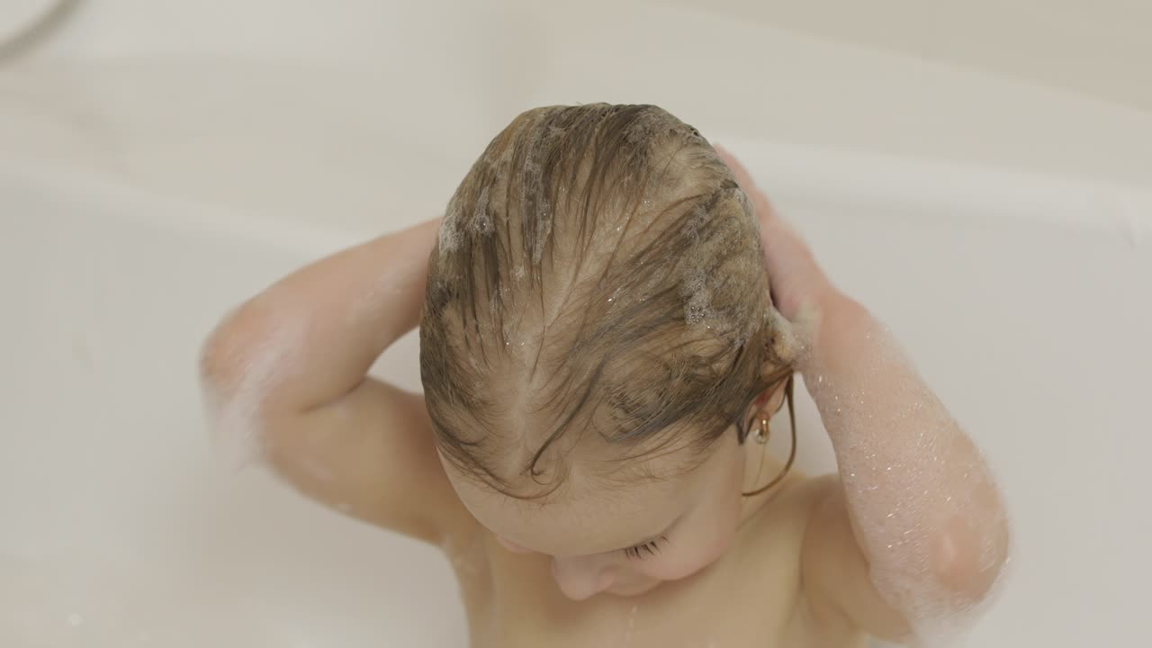 Bambina di tre anni carina che fa il bagno. Pulizia e lavaggio dei capelli