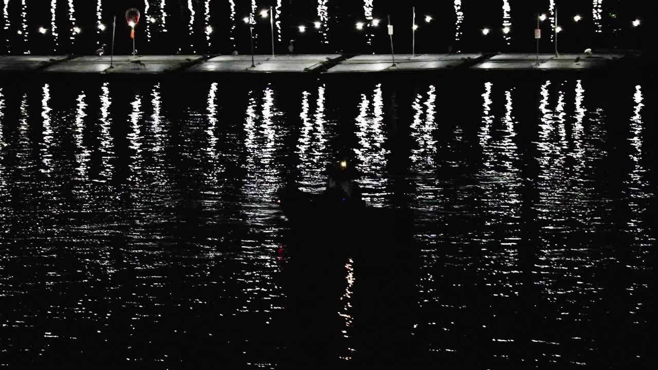 밤에 미끼 바지선 옆에 있는 보트의 실루엣