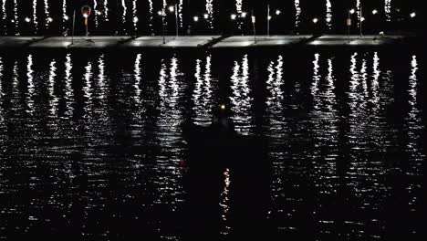 a-silhouette-of-a-boat-next-to-a-bait-barge-at-night