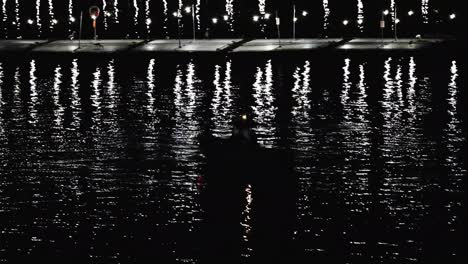 una silueta de un barco junto a una barcaza de cebo por la noche