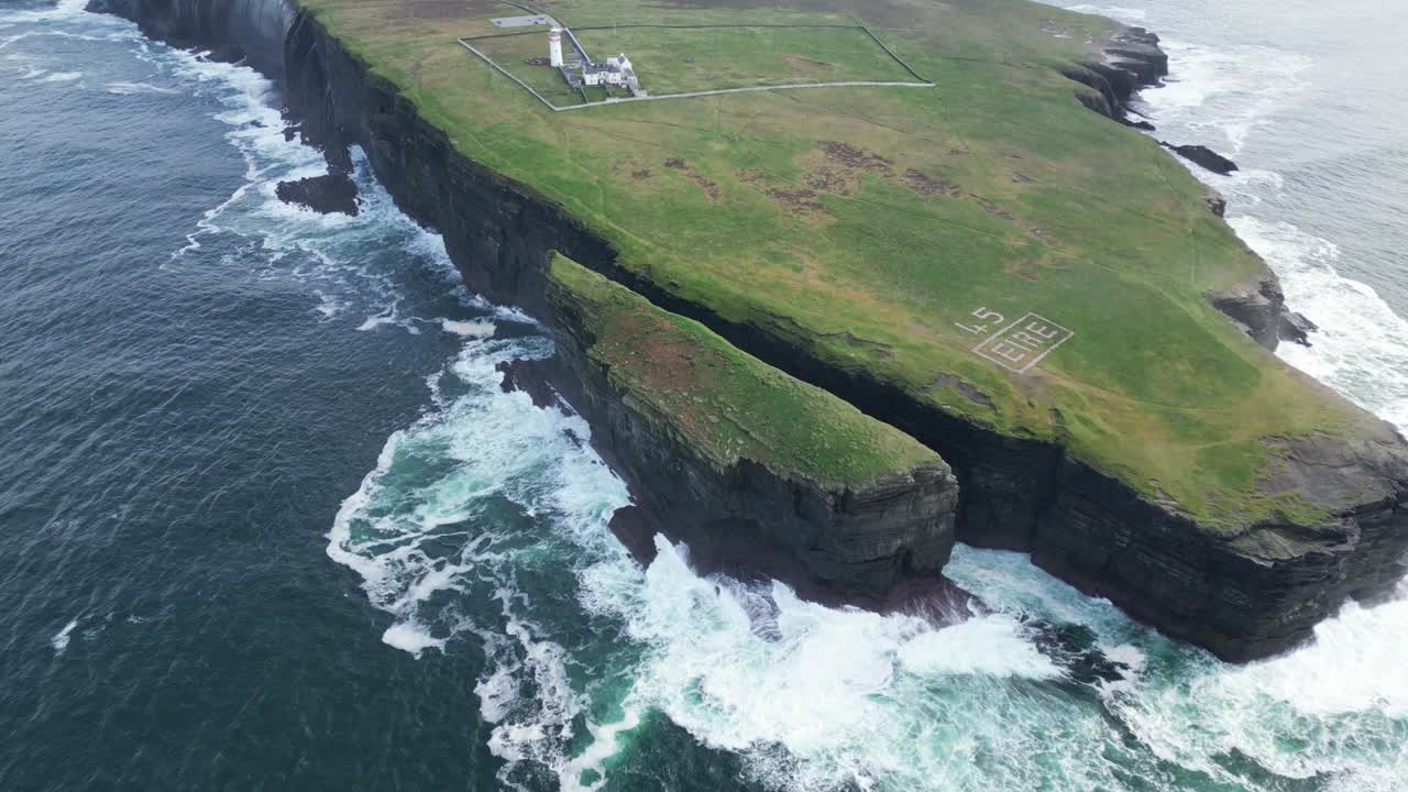 vista aérea de la escarpada costa con el signo "éire", las olas chocando contra los acantilados, marcador histórico