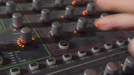 a person pressing the eq button on a music mixer board