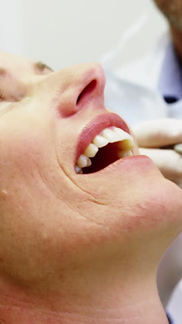 dentist examining a female patient with dental tools