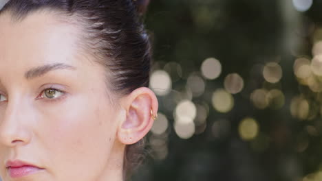 smiling woman enjoying sunny day outdoors with blurred greenery in background
