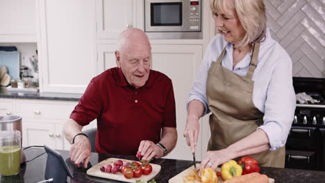 senior couple cooking healthy meal in kitchen with smart home technology