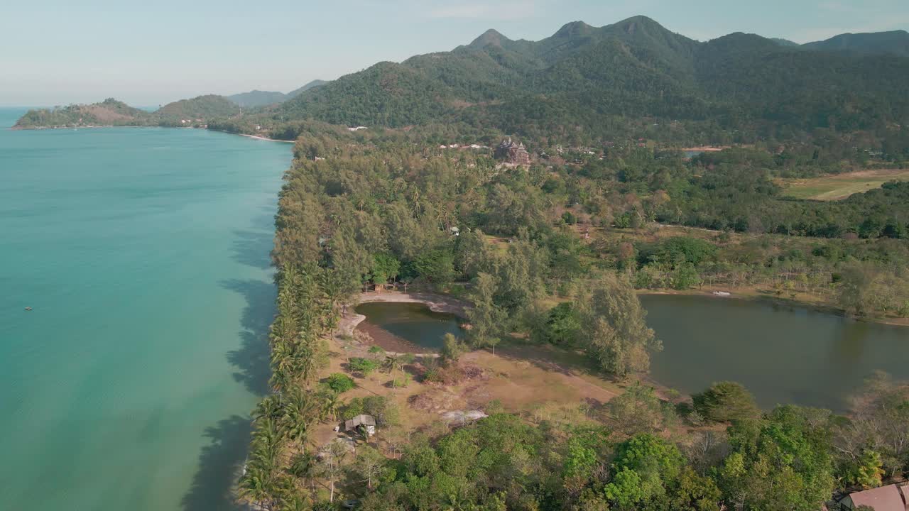 vista de drones sobre las palmeras en la playa costera vacía, con montañas en una isla tropical