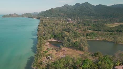 Vista-De-Drones-Sobre-Las-Palmeras-En-La-Playa-Costera-Vacía,-Con-Montañas-En-Una-Isla-Tropical