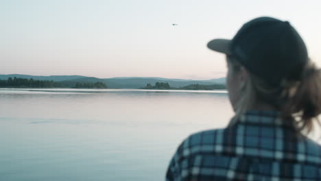 mujer viendo la puesta de sol sobre el lago