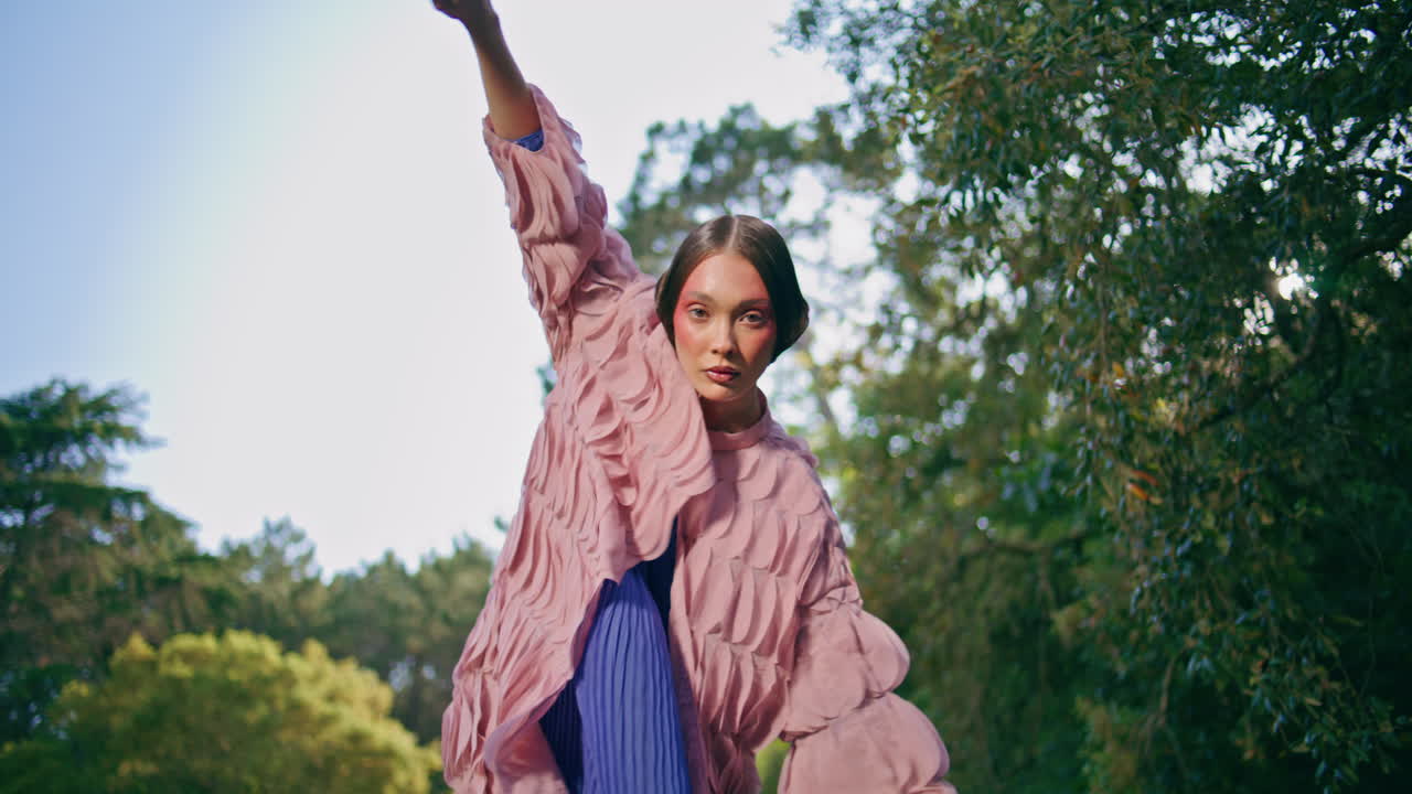una mujer inusual posando una hermosa naturaleza verde moviendo las manos como un pájaro volador.