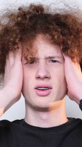 closeup of face of worried redhaired curly guy looking at camera closeup of face of worried redhaired curly guy looking at camera headache poblem fail trouble