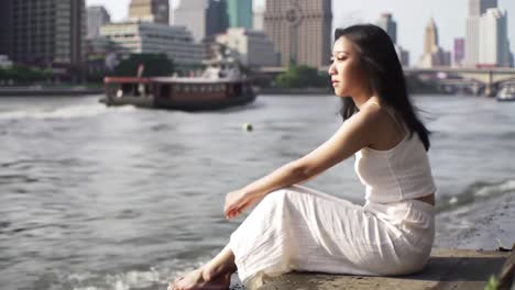 woman sitting by the river in a city