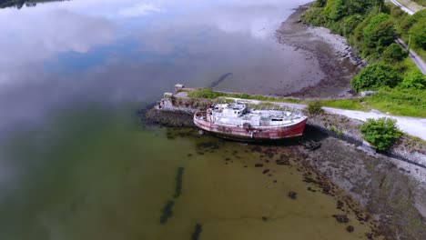 Abandoned-old-river-boat-and-a-pier,-drone-footage-circle-flying