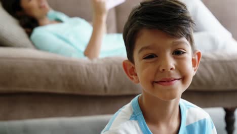 Portrait-smiling-boy-sitting-on-rug-in-living-room