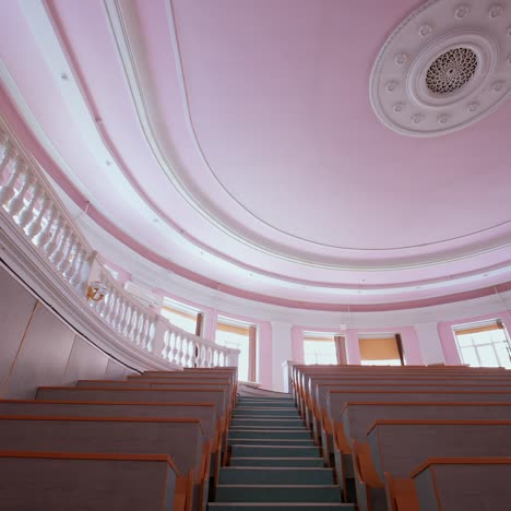 empty auditorium at university. large classroom with rows of wooden desks without students. steps among tables in the large lecture hall. pandemic