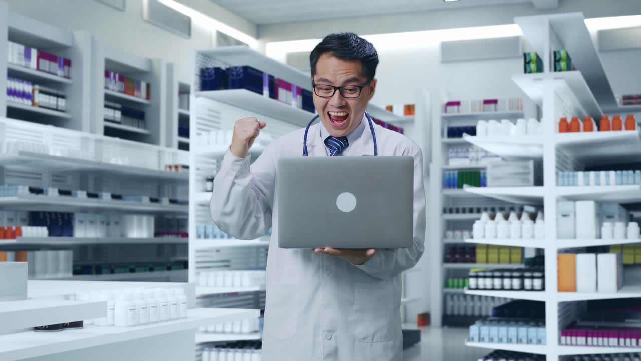 스테토스코프를 들고 노트북을 보고 약국에서 성공을 축하하는 아시아 남성 의사