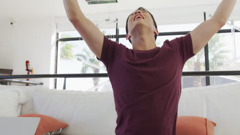 Happy-asian-male-teenager-using-vr-headset-and-playing-video-games-in-living-room