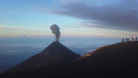 volcano erupting in the sunrise with a group of people watching from another volcano