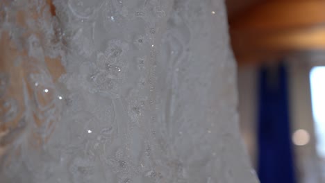 close-up of white lace wedding dress on hanger, sparkling with sequins and beads