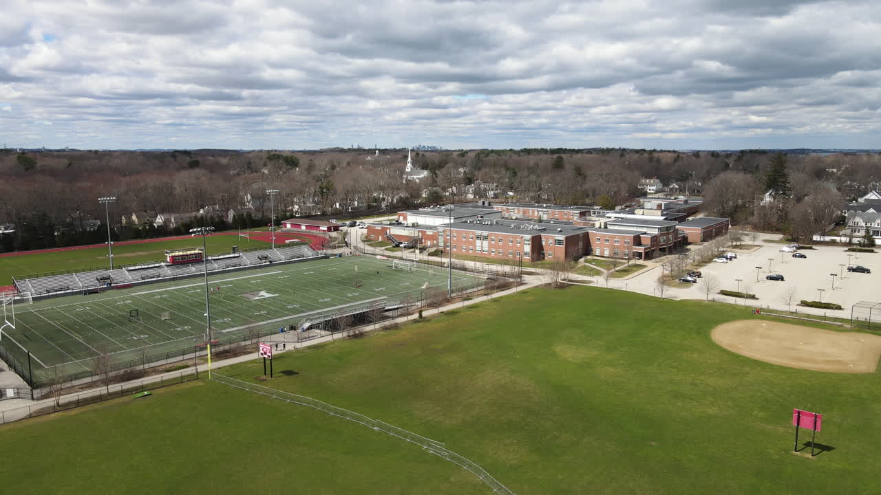 먼 거리에 보스턴 시가 있는 스포츠 경기장과 학교 상공에 드론이 촬영되었습니다.