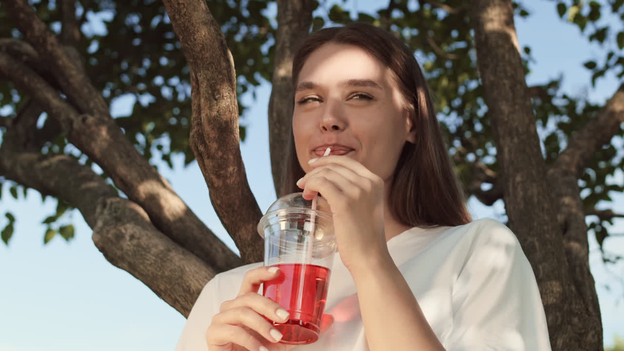 Woman Having Soft Drink by Tree