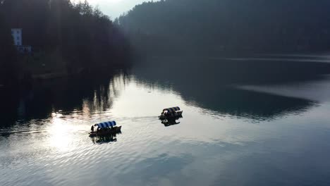aerial view over calm morning lake bled with two boats travelling across
