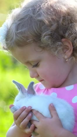 a little girl is holding a fluffy white rabbit enjoying the moment