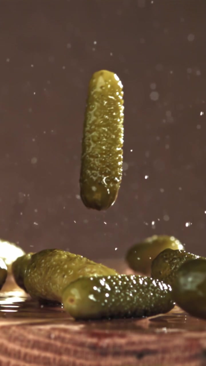 Ferske agurker som faller og plasker på en treoverflate i sakte film