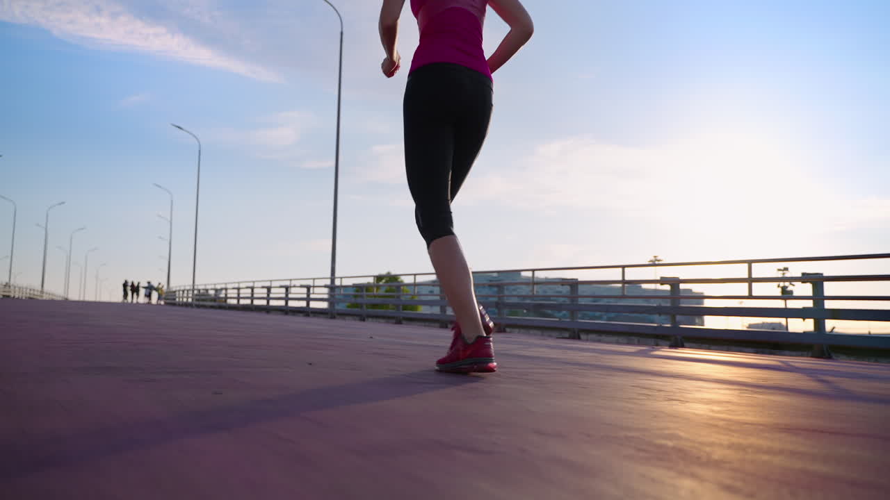 mujer corriendo en un puente de la ciudad al atardecer
