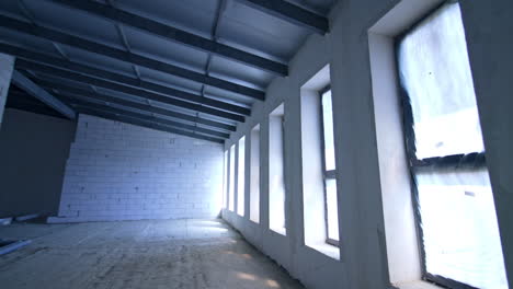large room with multiple big long windows. white brick walls and new roof in the building.