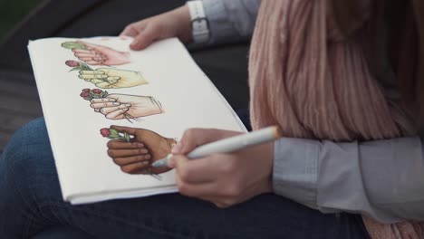 mujer dibujando manos sosteniendo flores