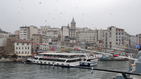 istanbul galata tower view with fishermen on bridge and flying birds