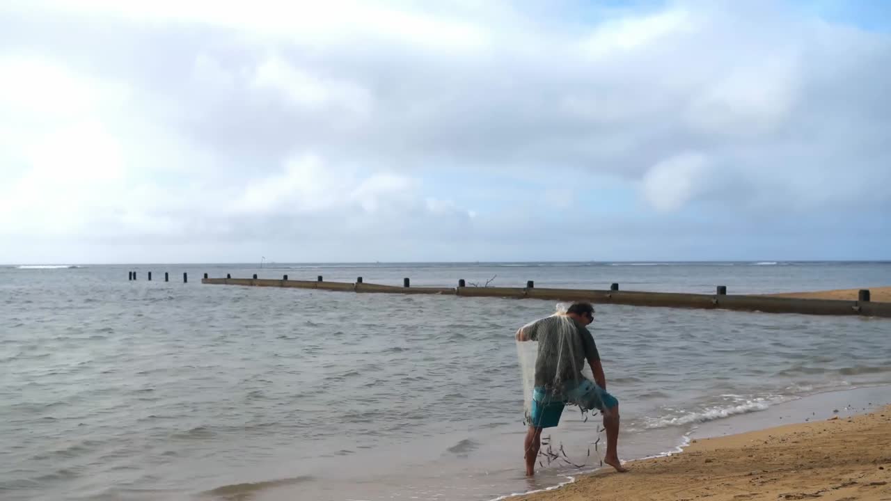 pescador con red de pesca en la playa 4k