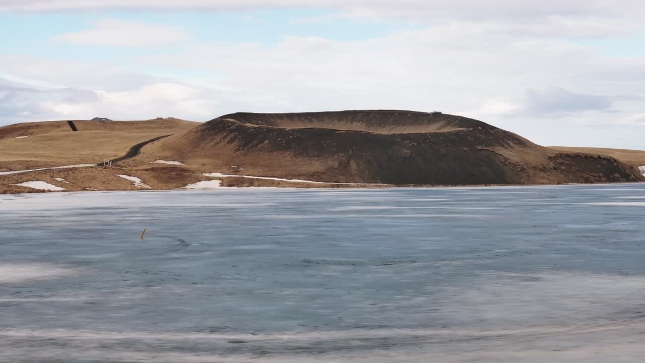 Lonely volcanic crater by frozen lake near Skútustaðir, Mývatn in early spring light