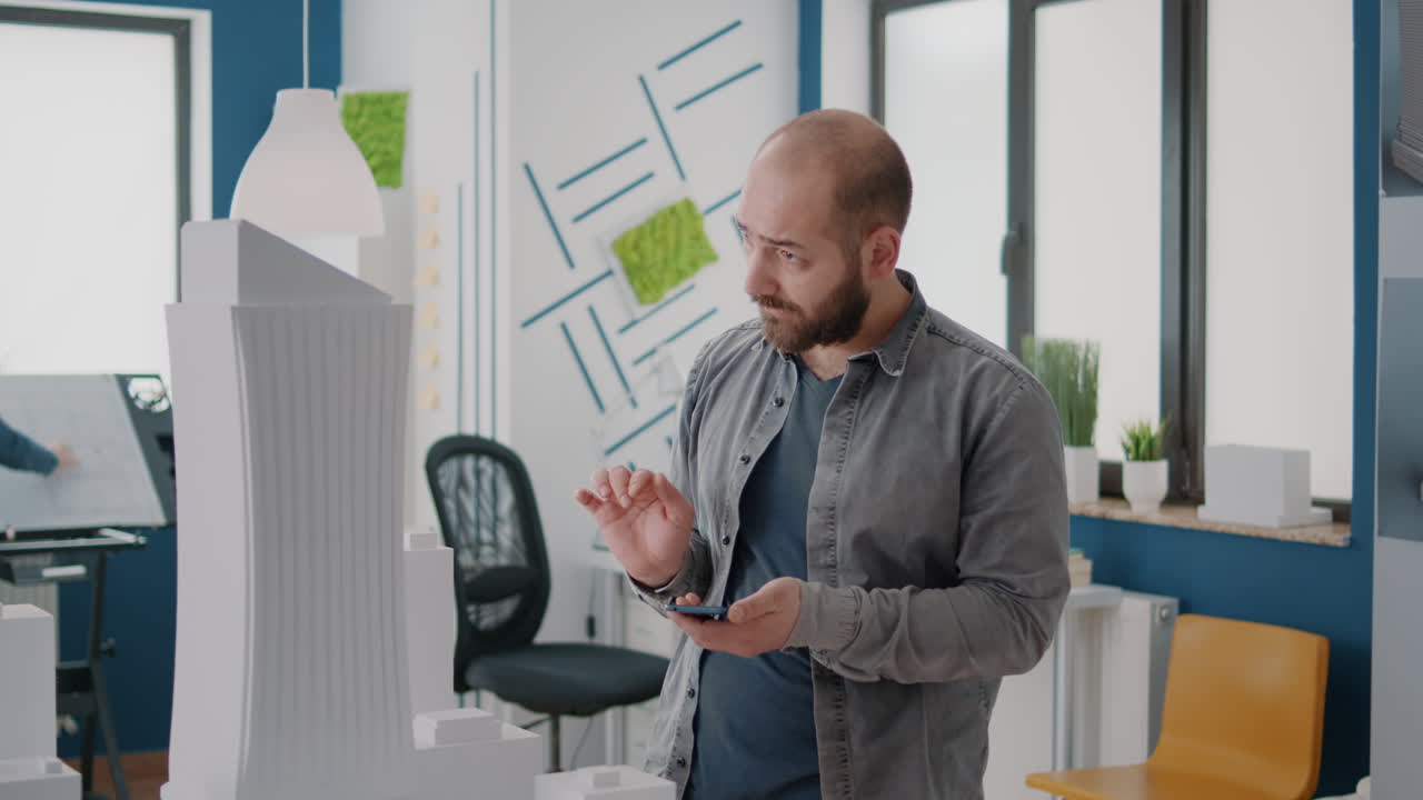 Architects working on building model and using smartphone in office