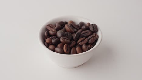 roasted coffee beans in a small bowl taken from a white table