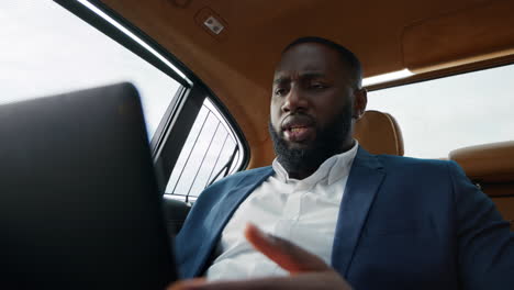 closeup serious african american man having video call on tablet computer at car