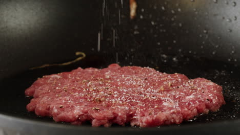 cooking raw hamburger patty in a pan