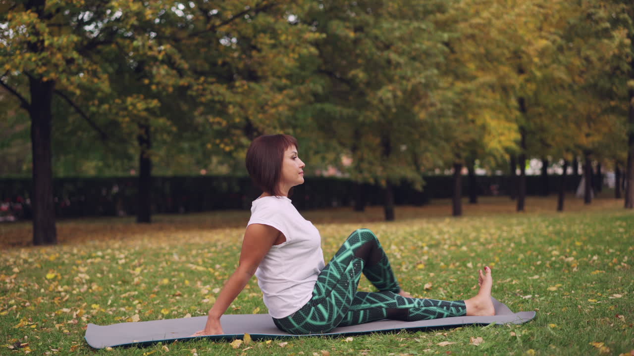 Woman practicing yoga in a park during autumn