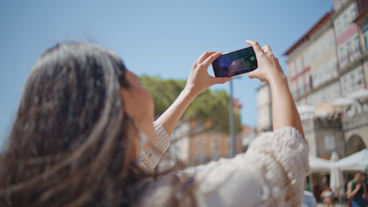 Tourist taking  pictures of town architecture on summer trip back view