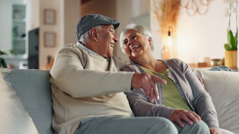happy elderly couple sitting on a couch and smiling at each other