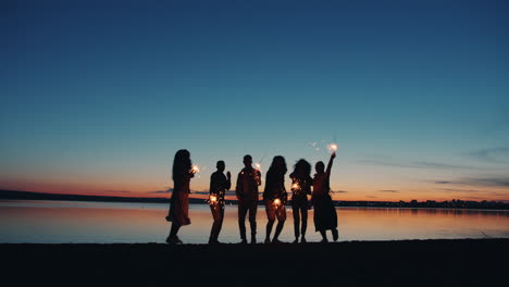 friends celebrating sunset on the beach with sparkler
