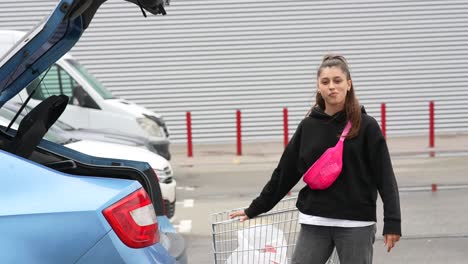 adolescente cargando un coche con un carrito de compras