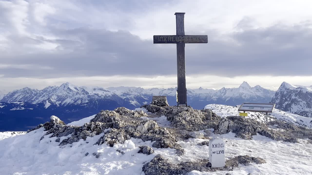 View from peak of Untersberg mountain in Germany with a cross and view of snow-capped mountains in the Alps