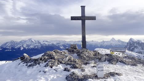 view from peak of untersberg mountain in germany with a cross and view of snow-capped mountains in the alps