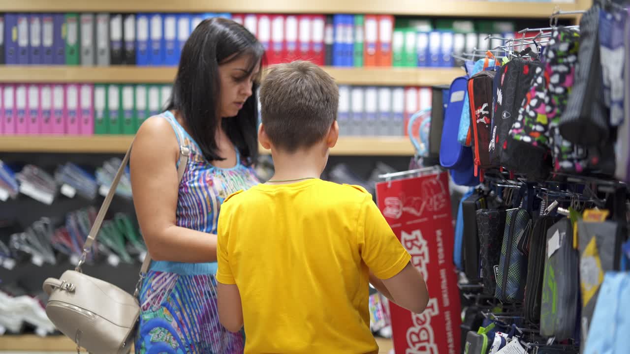 Family buying school supplies. Boy choosing school supplies with mother in stationery shop